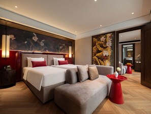Una habitación de hotel moderna con una cama grande, un sofá y una mesita de centro roja.