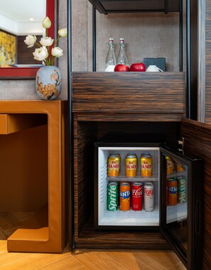 Un miniibar con bebidas y un florero con flores.