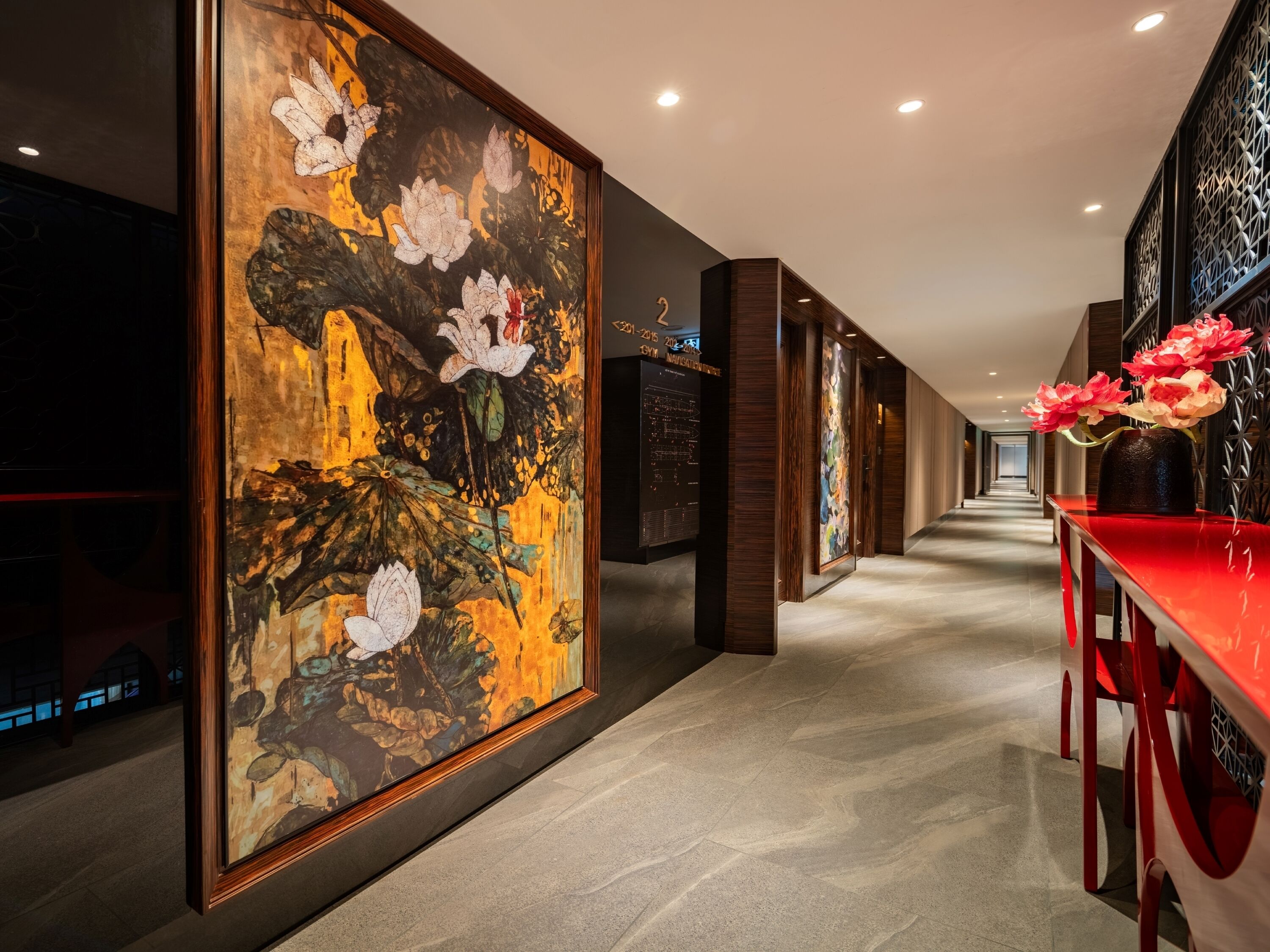Um corredor com uma grande pintura floral, uma mesa vermelha com flores e design moderno.