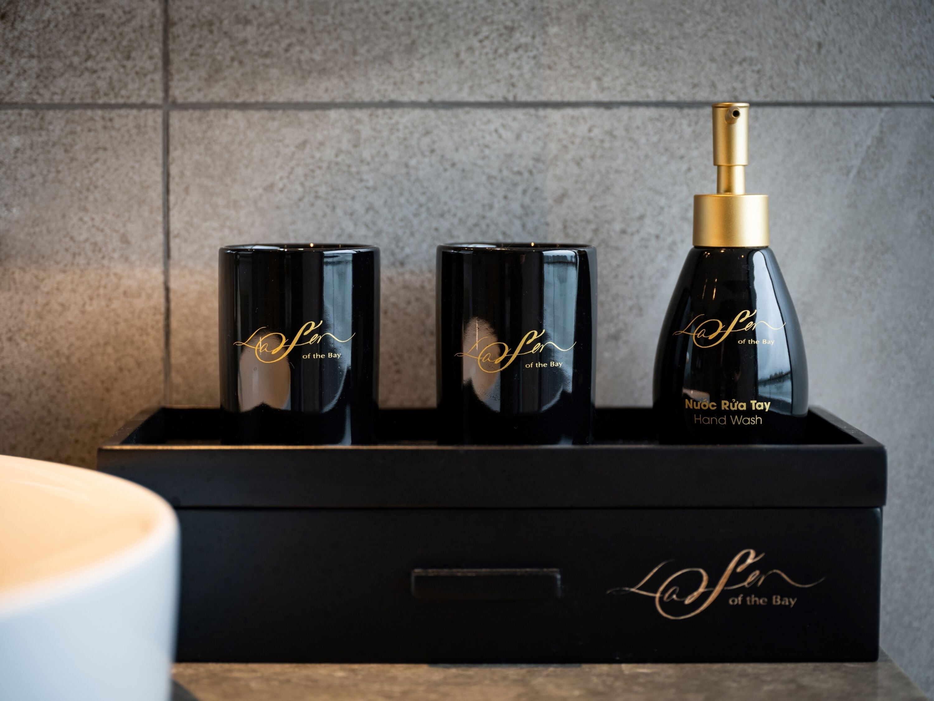 A black box containing three black bottles with gold accents and a gold spray nozzle.
