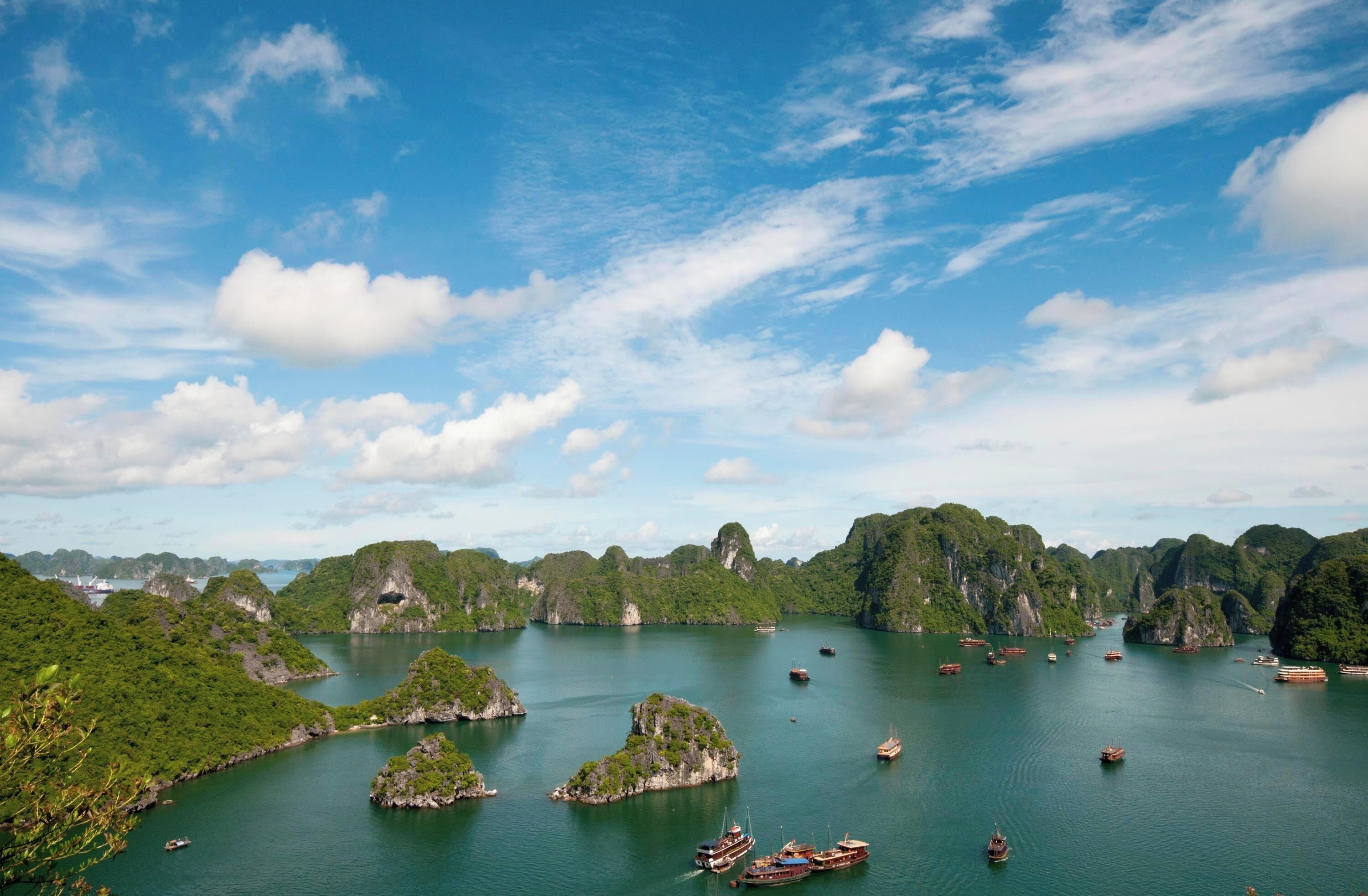 A coastal landscape with numerous boats, rocky islands, and lush greenery.