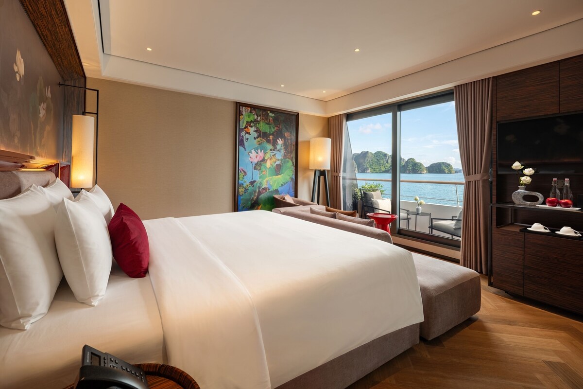 Habitación de hotel moderna con una cama grande, televisión y vista a un cuerpo de agua.