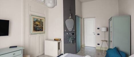 Habitación de hotel con cama, escritorio, armario, espejo, un cuadro y televisor.