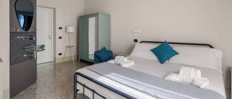 A hotel room with a bed, a wardrobe, a mirror, a sink, and a lamp.