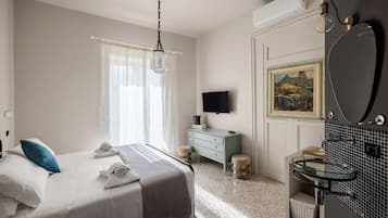 A bedroom with a bed, a dresser, a television, and a bathroom with a sink and mirror.