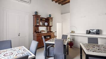 A dining area with a wooden cabinet, a white wall, and a ceiling with exposed beams.