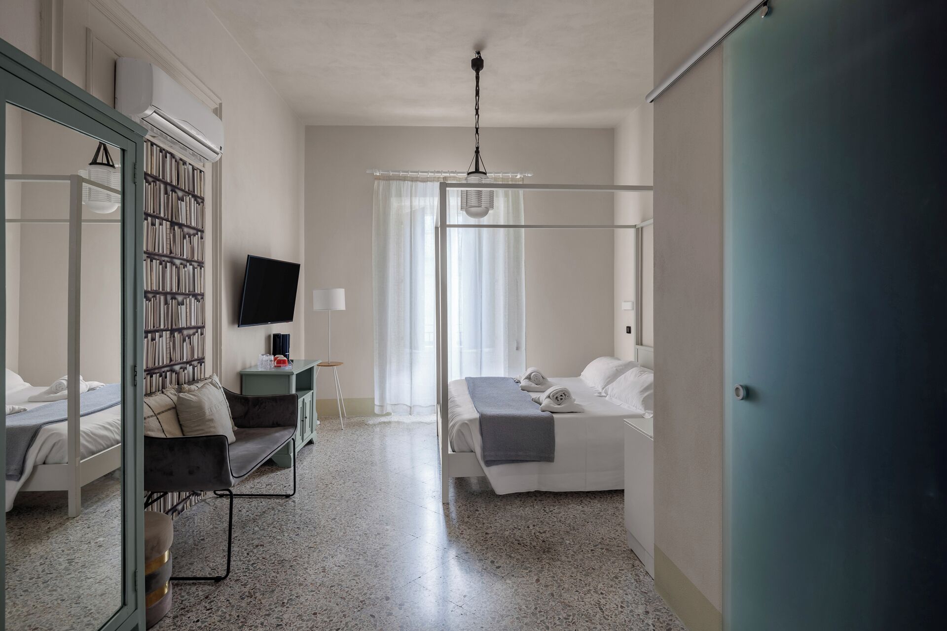 Ein Hotelzimmer mit Bett, Nachttisch, Lampe und Bücherregal.