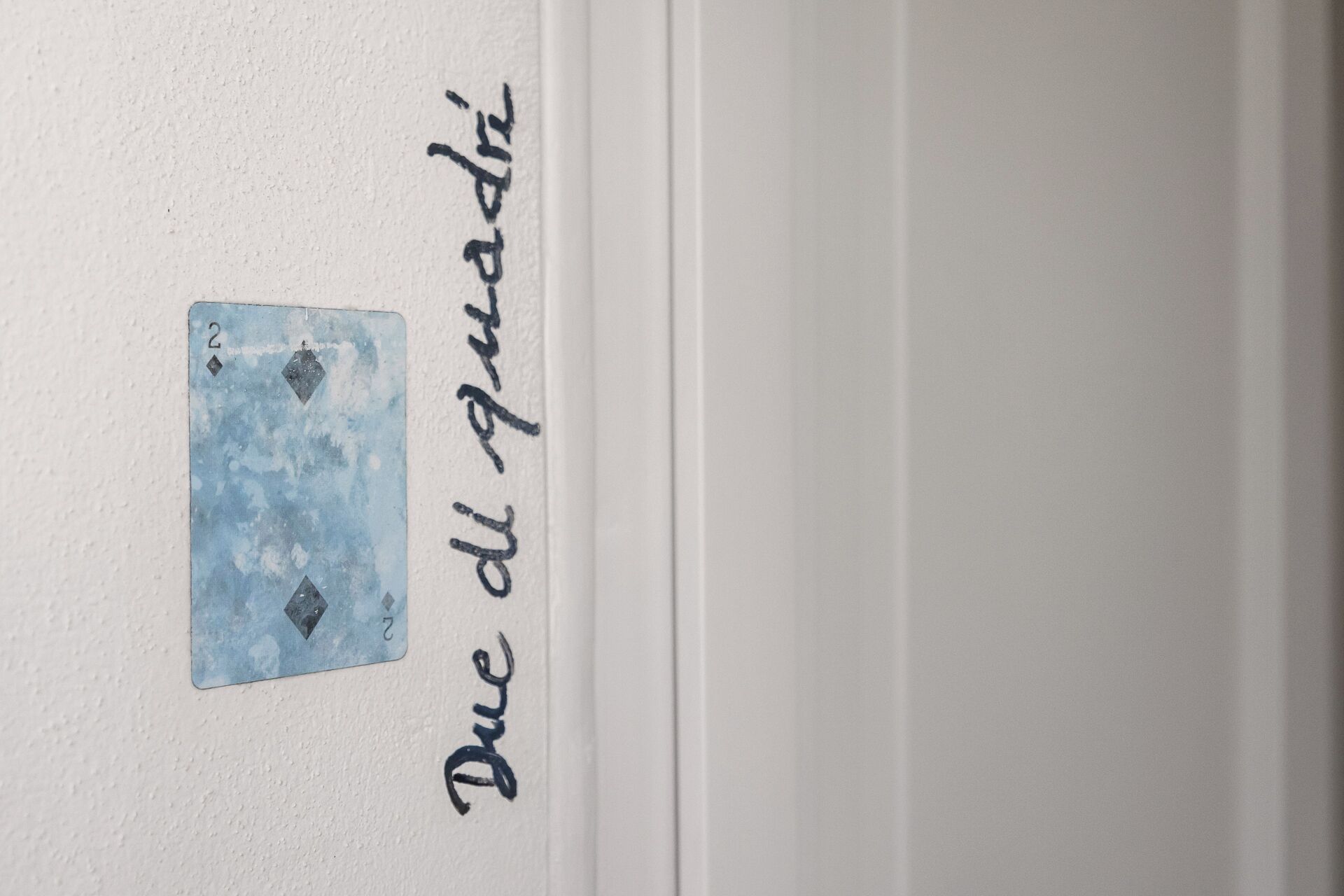 A wall with a blue card and the text 'Due del Quarti' written vertically.