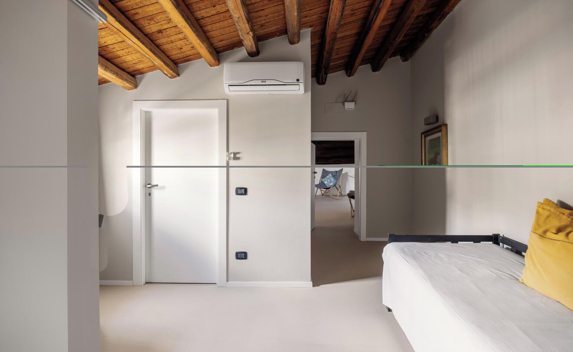 Ein Schlafzimmer mit einem Bett, einem Sessel, einem Kleiderschrank und einer Klimaanlage.