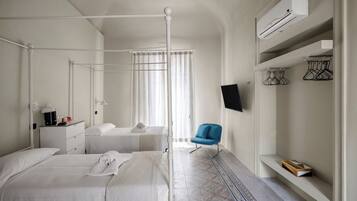 A hotel room with a bed, bedside table, lamp, air conditioning unit, TV, and a chair.