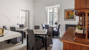 Ein Essbereich mit Tisch und Stühlen, einer Küchenzeile, einem Heizkörper und einem Bild an der Wand.