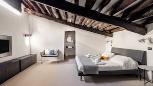 Ein Schlafzimmer mit Bett, Fernseher, Schreibtisch, Stuhl und eigenem Bad.
