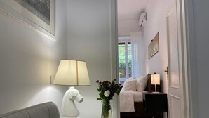 Um quarto moderno com uma cama, luminárias de cabeceira, um vaso com flores e uma janela com cortinas.