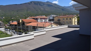 Eine Dachterrasse mit Blick auf einen Berg, Gebäude und einen klaren Himmel.