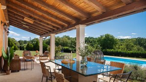 An outdoor patio with a glass table, wicker chairs, and a view of a swimming pool. - Villa Primavera with pool Grožnjan by Villas Guide (Grožnjan)
