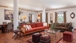 A spacious living room with a red sofa, a brown sofa, and a glass coffee table. There are two lamps, a dining area with a table and chairs, and a large painting on the wall. - Villa Primavera with pool Grožnjan by Villas Guide (Grožnjan)