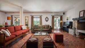 A spacious living room with a red sofa, a green sofa, and a patterned rug. There is a piano and a fireplace. - Villa Primavera with pool Grožnjan by Villas Guide (Grožnjan)