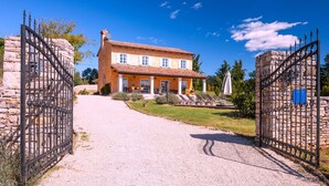 A two-story house with a gravel driveway leading to a gated entrance. - Villa Primavera with pool Grožnjan by Villas Guide (Grožnjan)