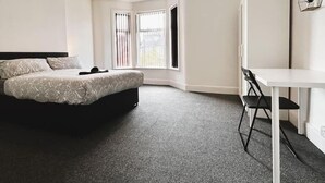 A modern bedroom with a bed, a desk, and a chair. - Salisbury Place by SG Property Group (Crewe)