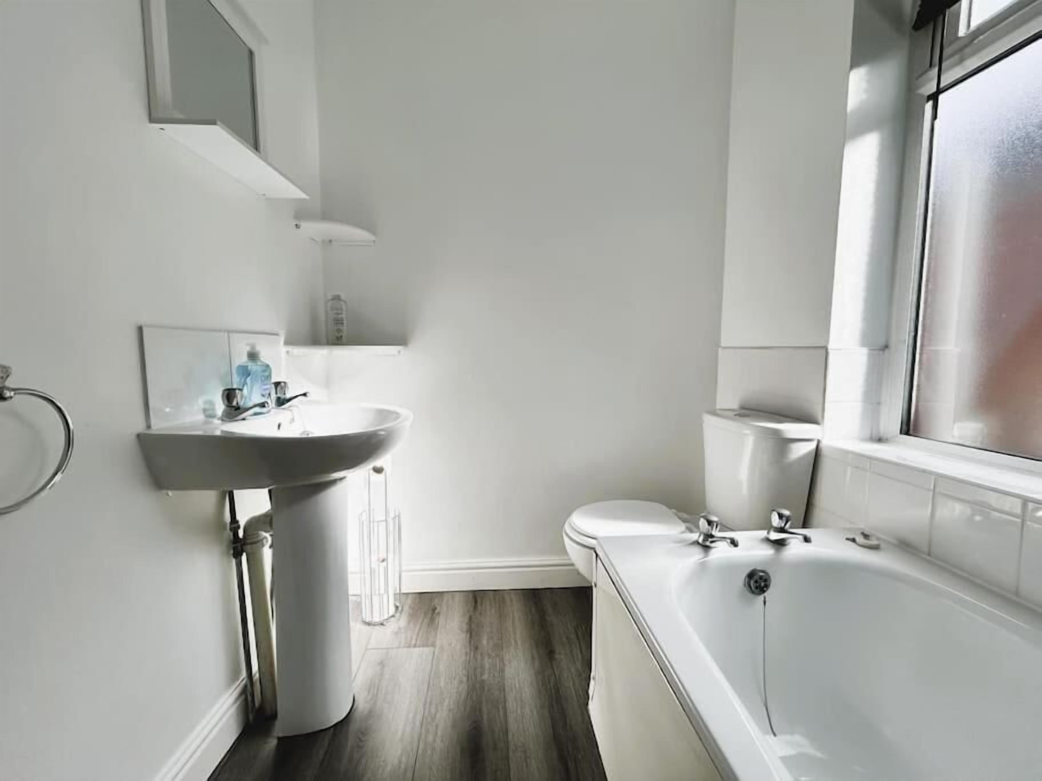Un bagno moderno con lavandino, water e vasca da bagno bianchi.