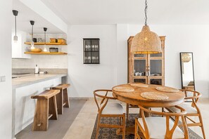 A modern kitchen with white cabinets, a wooden countertop, and a hanging light fixture.
