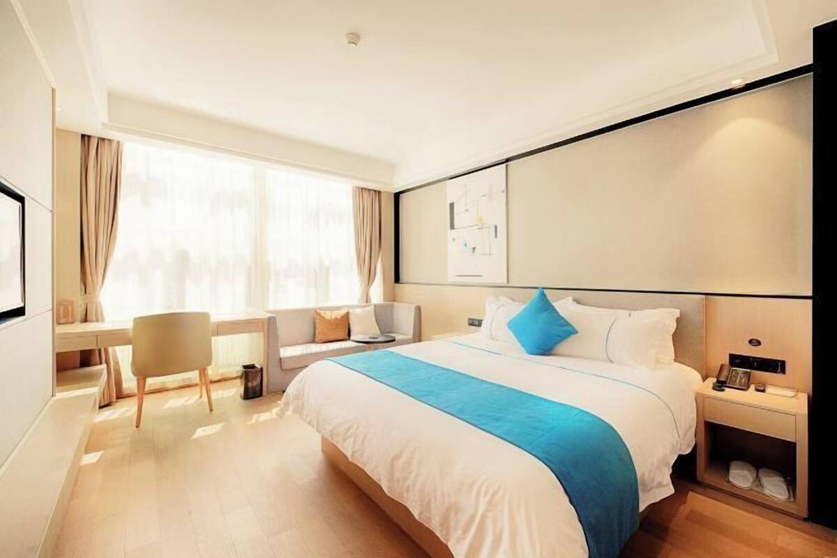 A modern hotel room with a large bed, a desk, and a chair.