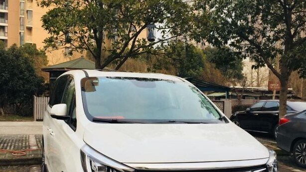 A white SUV parked in a parking lot with trees and a building in the background. - BOOEIN HOTEL (Suzhou)