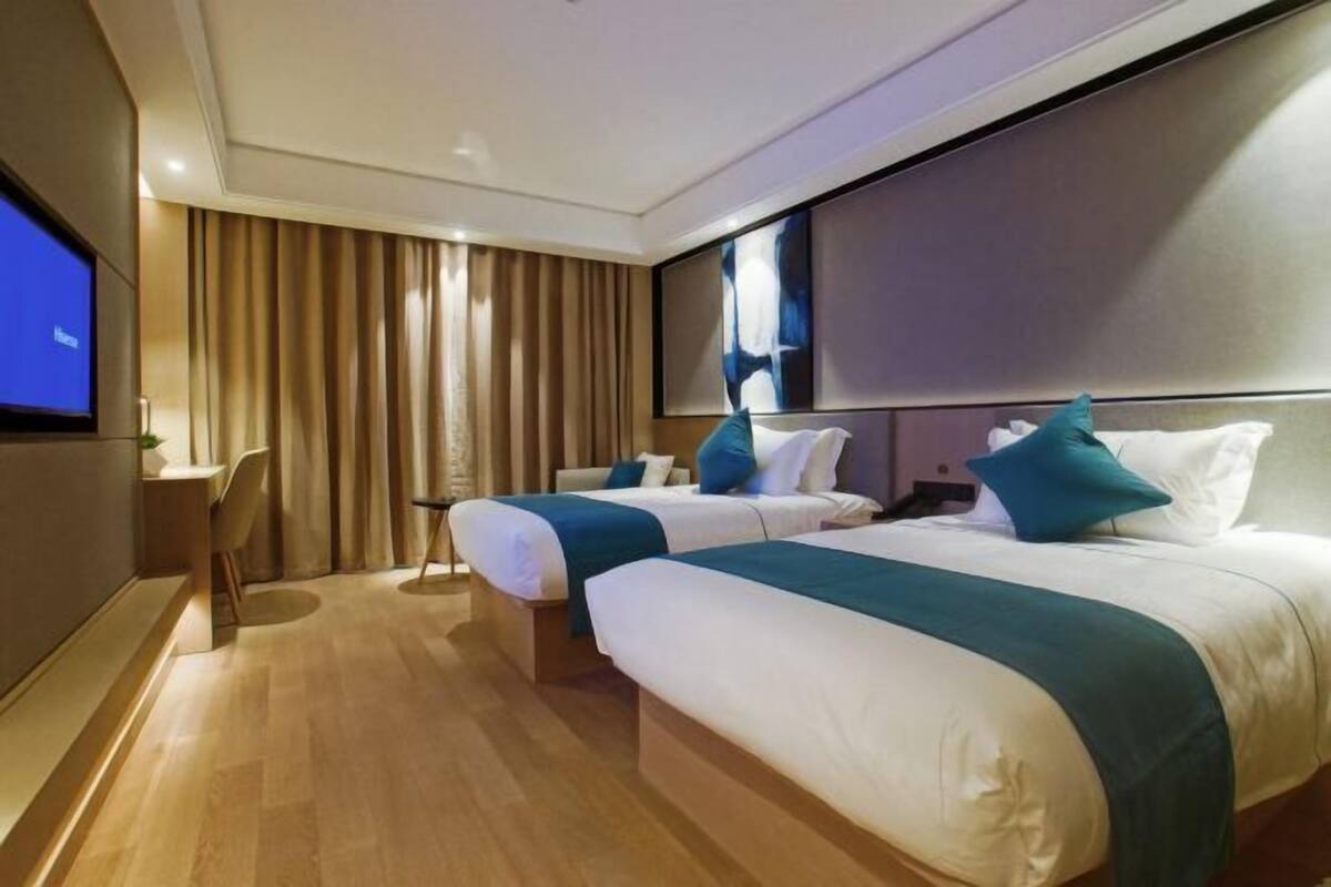 A hotel room with two beds, a desk, and a TV.