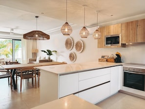 A modern kitchen with a central island, wooden cabinets, and pendant lights.