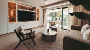 A modern living room with a flat-screen TV, built-in shelving, a ceiling fan, and a large plant.