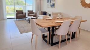 A modern dining area with a wooden table, six chairs, and a glass partition.