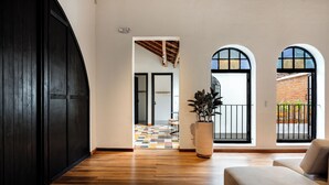 Un interior espacioso con piso de madera, una planta grande en maceta y un sofá.