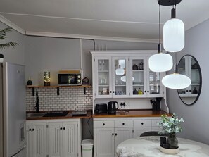 Une cuisine moderne avec des meubles blancs, un four à micro-ondes, un évier et un plan de travail en marbre.