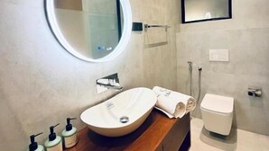 A modern bathroom with a wooden vanity, a round mirror, a white sink, and a toilet. - La Vizta Weligama (Weligama)