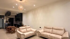 A modern living room with a beige sectional sofa, a wooden dining table, and recessed ceiling lighting. - La Vizta Weligama (Weligama)