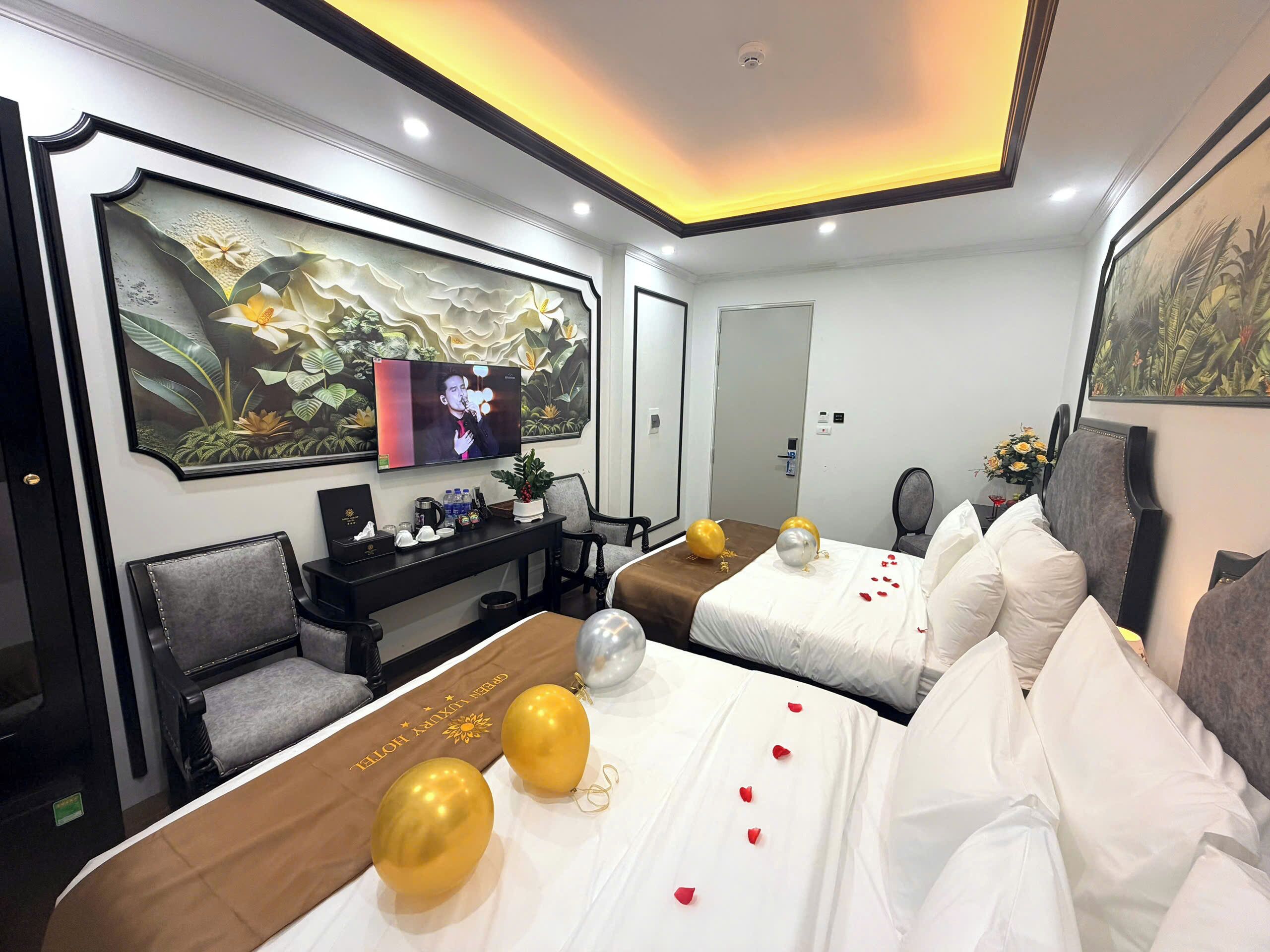 A hotel room with a bed, a desk, a chair, a television, and a large painting on the wall.