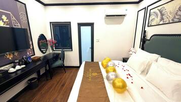 Una habitación de hotel con cama, mesita de noche, escritorio, silla y televisor.