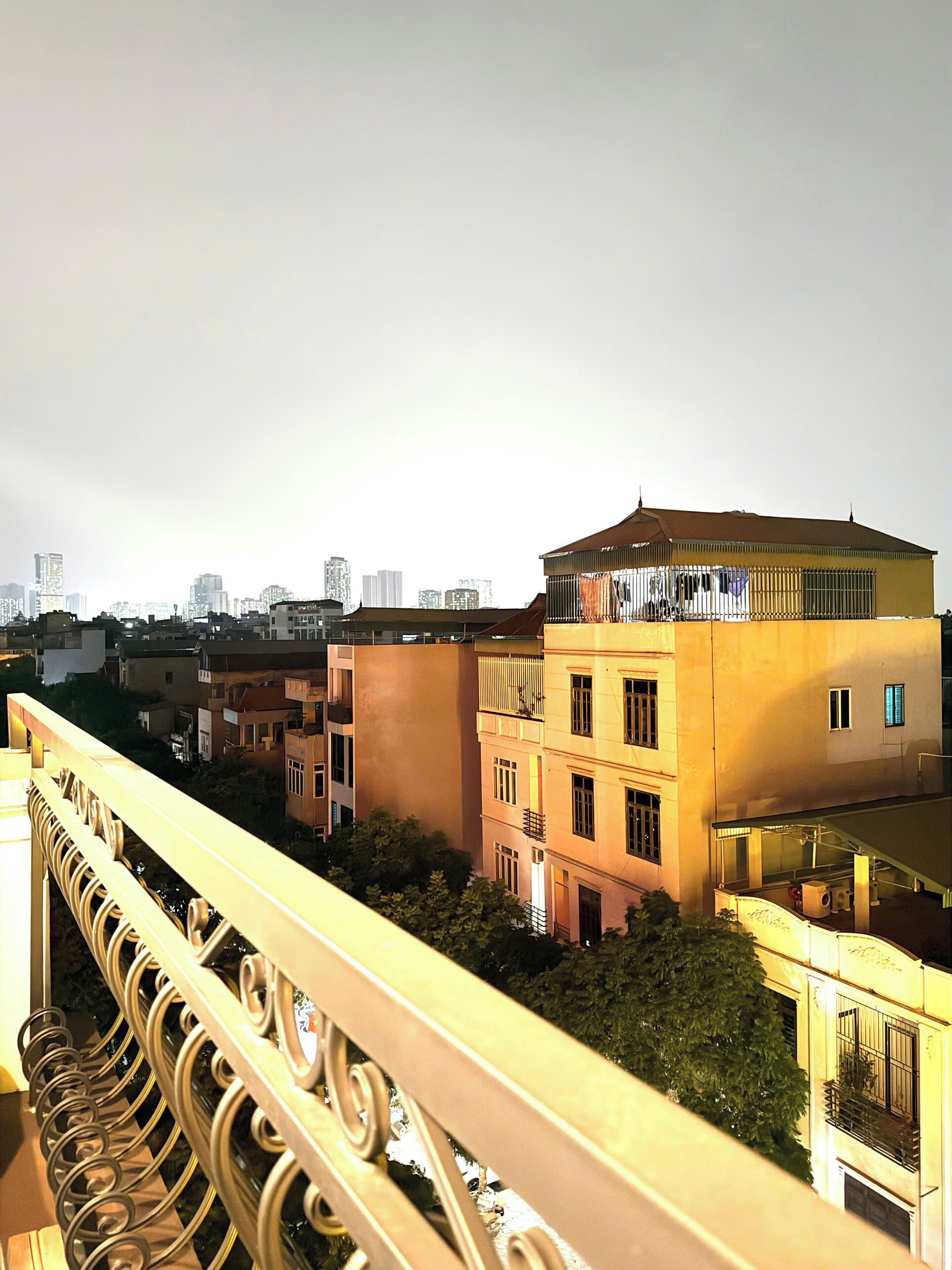 A building with balconies, a railing, and a cityscape in the background.