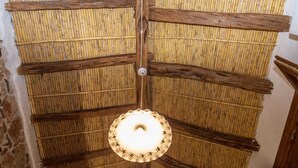 A ceiling with bamboo panels and a central wooden beam. - Domm'e Antoni - Apartment in the heart of Ogliastra in stone and juniper (Baunei)