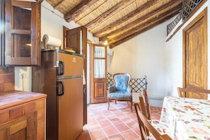 A compact kitchen with a wooden refrigerator, a dining area with a table and chairs, and a rustic ceiling. - Domm'e Antoni - Apartment in the heart of Ogliastra in stone and juniper (Baunei)