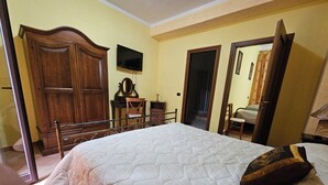 A bedroom with a bed, wooden wardrobe, television, and a mirror.