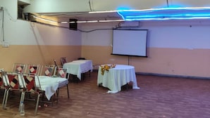 Une salle de conférence équipée d’un tableau blanc, d’un écran de projection et d’une table agrémentée d’un arrangement floral.