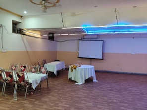 A conference room with a whiteboard, a projector screen, and a table with a floral arrangement.