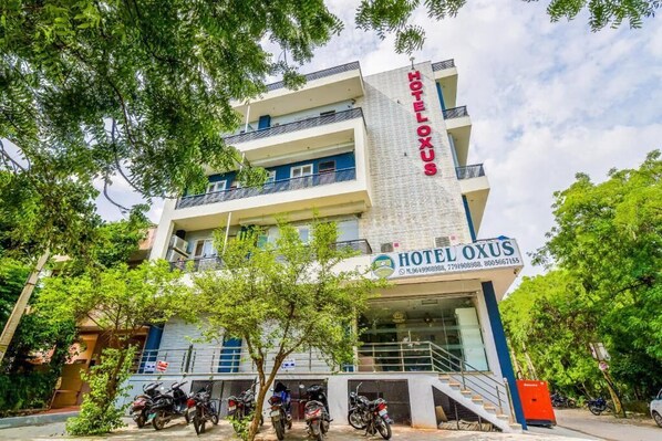 A multi-story hotel named Hotel Oxus with a prominent sign, balconies, and parked motorcycles.