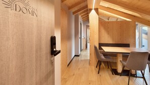 A wooden interior with a dining area, a door with a lock, and a hallway leading to another room. - Apartment '4 Bilocale Est' with Private Terrace (Livigno)