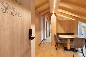 Een houten interieur met een eethoek, een deur met slot en een gang naar een andere kamer.