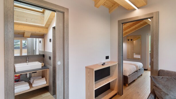 A modern bedroom with a skylight, wooden beams, a built-in TV, and a large mirror. - Apartment '4 Bilocale Est' with Private Terrace (Livigno)