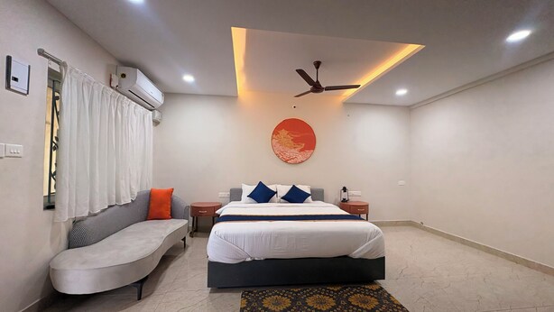 Une chambre d’hôtel moderne équipée d’un lit, d’un canapé, d’une petite table et d’un ventilateur de plafond.