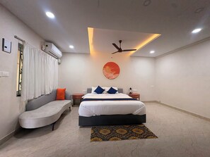 Una moderna camera d'albergo con un letto, un divano, un tavolino e una ventola a soffitto.