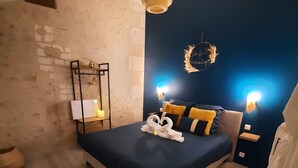 A bedroom with a bed, bedside lamps, a wall-mounted light fixture, and a decorative wreath.